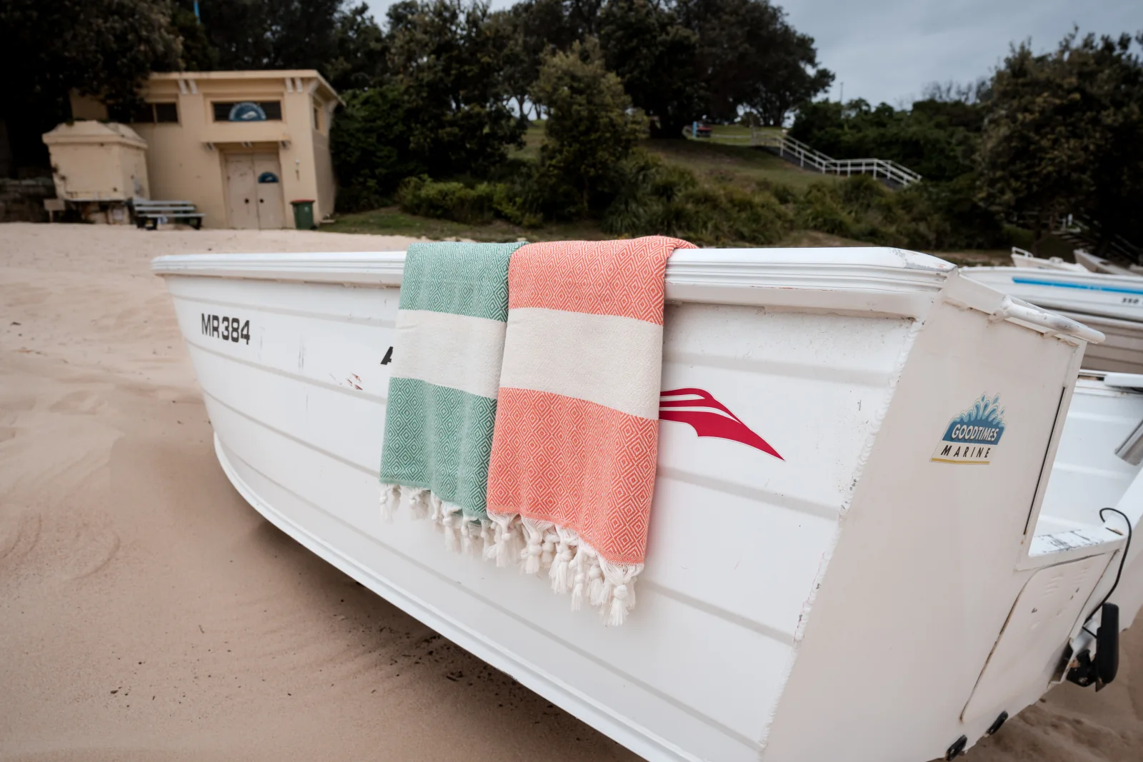 Green and coral diamond-weave foutas draped over a beach boat