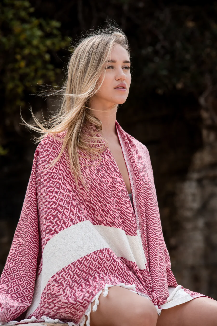 Woman wrapped in a red diamond-weave fouta in coastal light